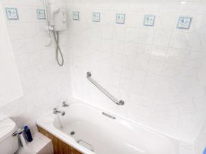 a white bathroom with a tub and a toilet at The Stable in Foxham