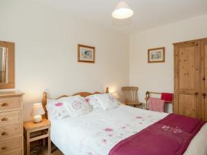 a bedroom with a bed and a wooden dresser at The Stable in Foxham