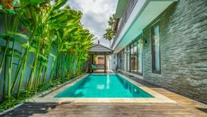 una piscina en el patio de una casa con plantas en Sotis Villas, en Canggu