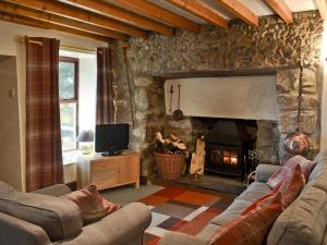 a living room with a stone fireplace with couches and a television at Llwyn Y Brig Isaf in Trevor