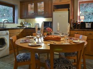 a kitchen with a wooden table with chairs and a table and a refrigerator at Llwyn Y Brig Isaf in Trefor