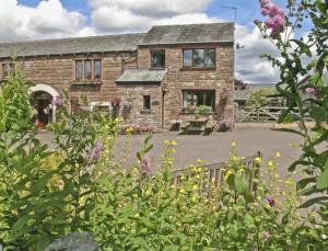 a stone house with a garden in front of it at Rundales Cottage in Appleby