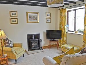 a living room with a fireplace and a television at Rundales Cottage in Appleby