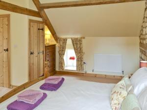 a bedroom with a large white bed with purple towels on it at Puffin Cottage in Bempton