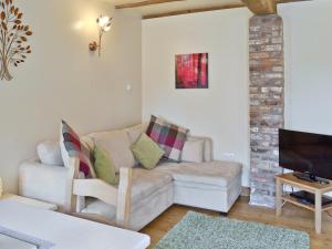 a living room with a couch and a tv at Puffin Cottage in Bempton