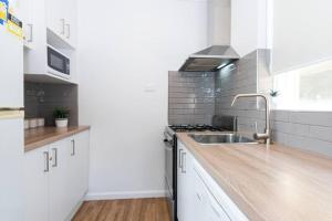 uma cozinha com armários brancos e um lavatório em Bright and Sunny Gem on Hotham em Melbourne