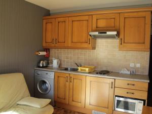 eine Küche mit Holzschränken, einer Spüle und einer Waschmaschine in der Unterkunft Studio Châtel, 1 pièce, 2 personnes - FR-1-200-236 in Châtel