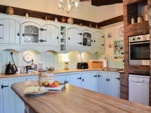 a kitchen with blue cabinets and a wooden table at Tranquillity Cottage in Winfrith Newburgh