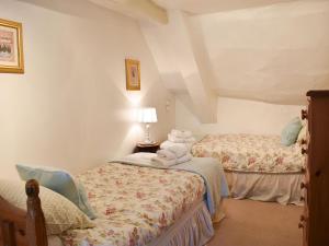 a bedroom with two beds and a lamp at Tranquillity Cottage in Winfrith Newburgh