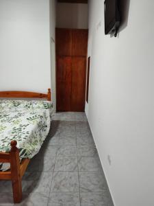 Un dormitorio con una cama y un televisor en una pared. en Alojamiento Turistico Mainque, en Las Grutas 4 fotos más