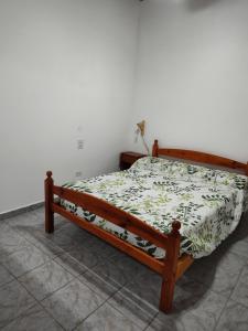 Cama de madera en un dormitorio con colcha de flores en Alojamiento Turistico Mainque, en Las Grutas