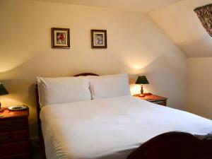1 dormitorio con 1 cama blanca grande y 2 lámparas en Timberwick Green-med, en Akeld