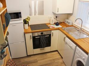 a kitchen with a white refrigerator and a sink at Nutmeg Cottage in Tideswell