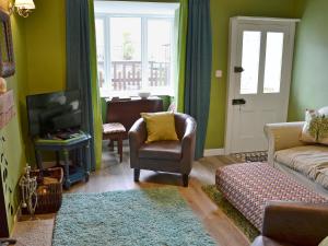 ein Wohnzimmer mit einem Sofa und einem TV in der Unterkunft Nutmeg Cottage in Tideswell