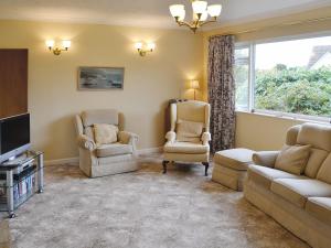 a living room with two chairs and a tv at Goonlaze in St Austell