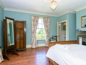 um quarto com paredes azuis, uma cama e uma janela em Tilney Hall em Terrington Saint John