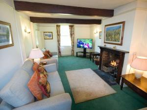 a living room with a couch and a fireplace at Swiss Cottage in Chideock