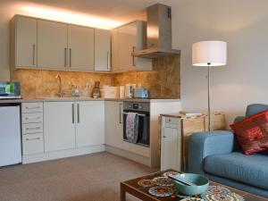 a kitchen with white cabinets and a blue couch at The Retreat in Nether Wasdale