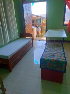 una camera da letto con due letti, un tavolo e una finestra di CJ Transient house a Baguio