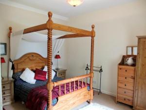 een slaapkamer met een houten bed met een houten frame bij Brightwater Cottage in Arnisdale