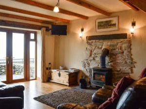 a living room with a stone fireplace with a stove at Beudy Bach in Nantlle