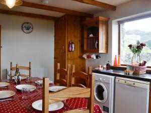 a kitchen with a table with a washing machine at Beudy Bach in Nantlle