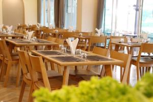 a dining room with wooden tables and chairs at The Leisure Hotel in Bang Bo