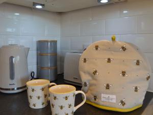 a counter with two mugs and two cups on it at The Honey House in Eastry