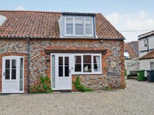 Casa de ladrillo con puerta blanca y ventanas en Wherry Cottage, en Wells-next-the-Sea