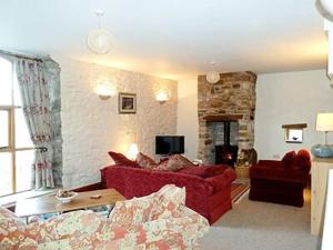 a living room with two red couches and a fireplace at Lord Mayors Barn in Alston