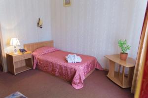 a small bedroom with a pink bed and two tables at Laetu in Atyraū