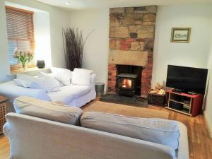 a living room with two couches and a fireplace at Bumble Cottage in Newton on the Moor