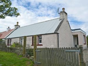 an old house with a fence in front of it at The Cottage in Duirinish