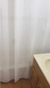a bathroom with a white shower curtain and a sink at Pearl of the City NEW KINGSTON in Kingston