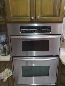 a stainless steel oven in a kitchen with wooden cabinets at Pearl of the City in Kingston