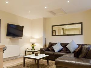 a living room with a leather couch and a mirror at Kinneddar Cottage in Saline