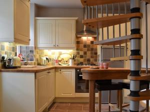 cocina con armarios blancos y encimera de madera en Pegs Place, en Windermere