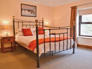 1 dormitorio con 1 cama con almohadas de color naranja y ventana en Ysgubor Wen en Burry Port