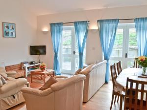 a living room with blue curtains and a table at The Cobbles in West Pennard