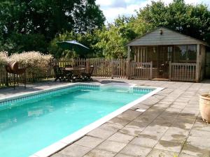 una piscina en un patio con cenador en The Old Granary, en Newent