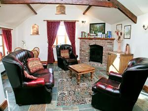 a living room with leather furniture and a fireplace at Parlour Cottage in Evershot