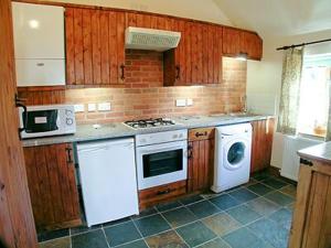 a kitchen with a stove and a washer and dryer at Parlour Cottage in Evershot