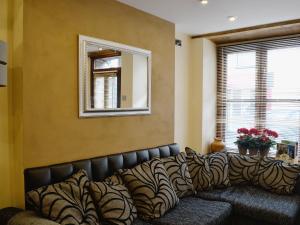 a leather couch in a room with a mirror and a window at The Tiny Terrace in Llandybie