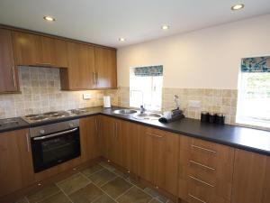 a kitchen with wooden cabinets and a black counter top at Somer Leyton Cottage in Chapel Saint Leonards