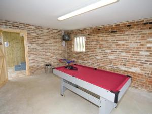 a ping pong table in a room with a brick wall at Somer Leyton Cottage in Chapel Saint Leonards