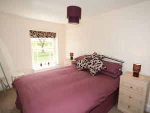 a bedroom with a bed with purple sheets and a window at Somer Leyton Cottage in Chapel Saint Leonards