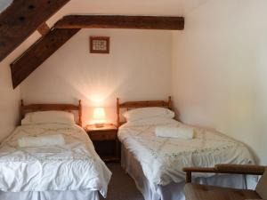 two twin beds in a room with two lamps at Lletty Cottage in Capel-Ifan