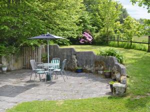 a patio with a table and chairs and an umbrella at Stowford Linhay - E3138 in Lewdown