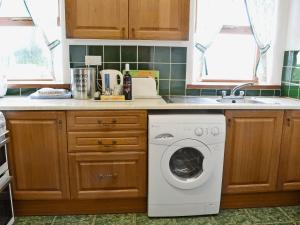 a kitchen with a washing machine and a sink at Beech Lodge in Buckland Brewer