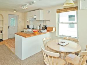 a kitchen and dining room with a table and chairs at Poppy - 28865 in Stokeinteignhead